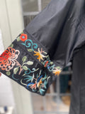 Close-up of a black silk Chinese embroidered garment sleeve featuring colorful floral embroidery